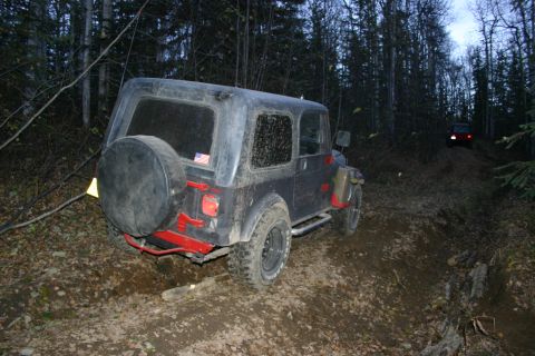 2003 Jeep TJ - Two Jeeps navigate a muddy, wooded trail in the fall.