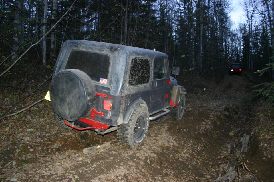 2003 Jeep TJ on a wooded dirt trail with another Jeep in the distance