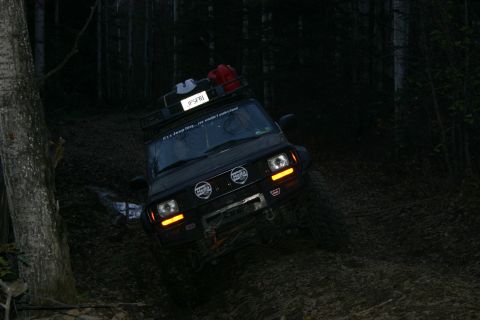 2003 Jeep TJ - A Jeep Cherokee XJ navigates a challenging off-road path through a dark forest.