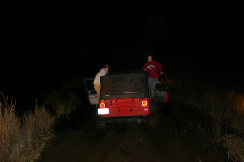 2003 Jeep TJ - Two individuals are near a red Jeep Wrangler at night, with its doors open.