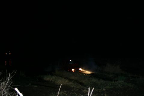 2003 Jeep TJ - A red Jeep is seen at night with its headlights illuminated and smoke billowing from the front of the vehicle.