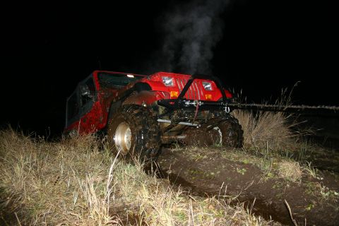 2003 Jeep TJ - Red 2003 Jeep TJ stuck in mud at night, steam rising from the engine compartment.