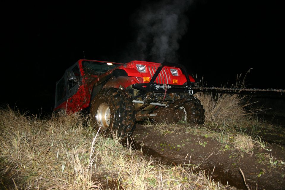 Red 2003 Jeep TJ stuck in mud, steam coming from hood, at night