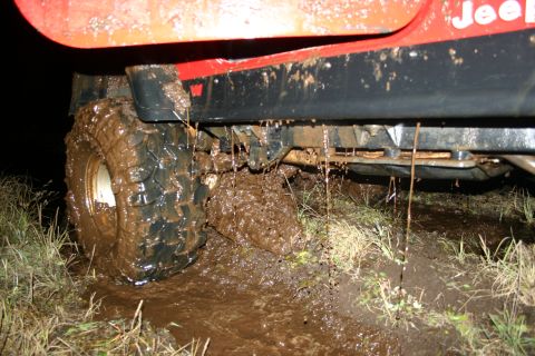 2003 Jeep TJ - This Jeep TJ is deep in mud, with water dripping from its undercarriage.