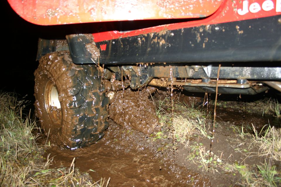 Jeep TJ stuck in mud, showing side panel and tire covered in mud