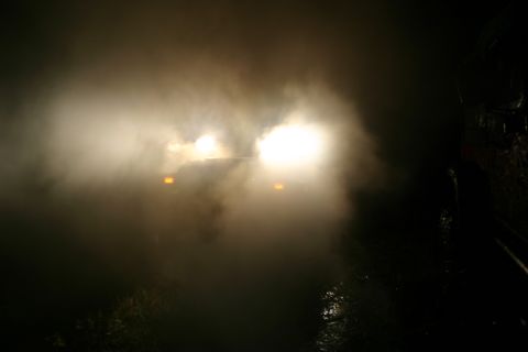 2003 Jeep TJ - A vehicle's headlights are visible through thick fog at night, obscuring details of the car.