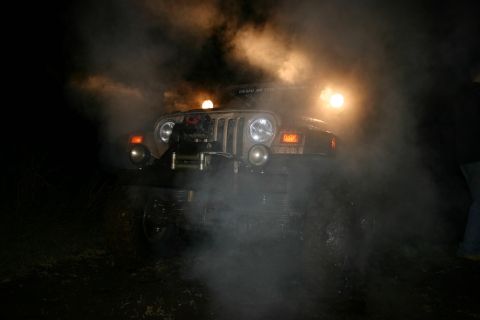 2003 Jeep TJ - A Jeep Wrangler is seen in the front view, partially obscured by smoke and illuminated by its headlights.