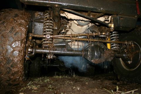2003 Jeep TJ - The underside of a vehicle is covered in mud, with visible suspension components and axles.