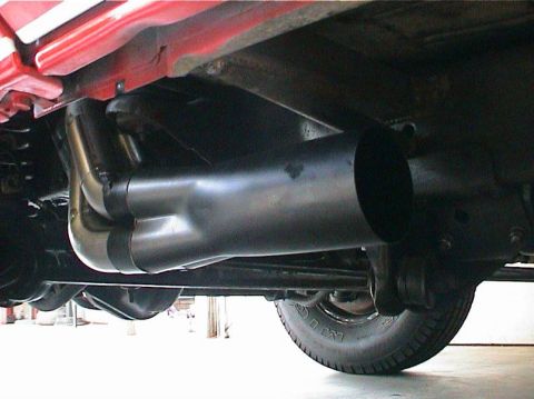 1979 Ford Bronco - Custom exhaust headers and pipe are visible on the underside of a vehicle, with a tire in the background.