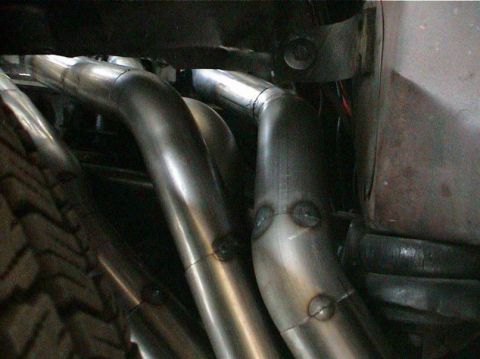 1979 Ford Bronco - Custom exhaust headers are visible next to a tire tread in this close-up shot.