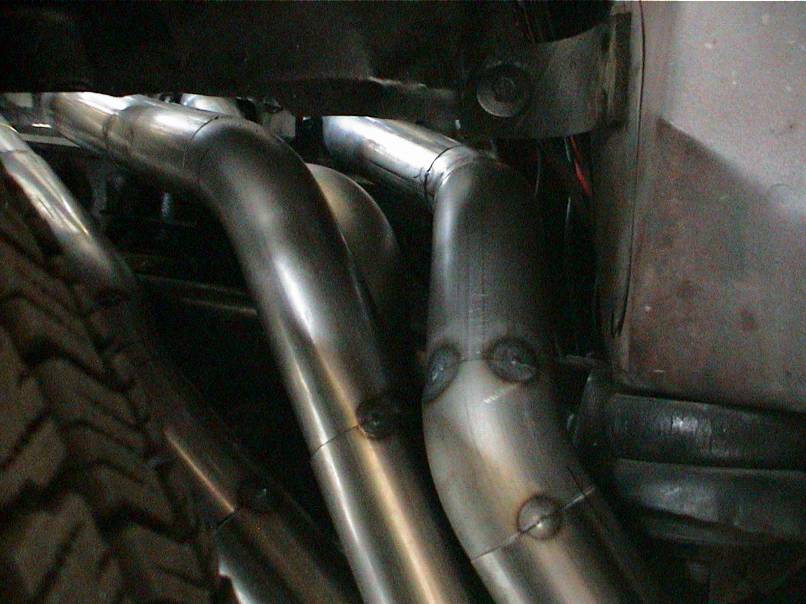 Close-up of custom exhaust headers and a tire tread