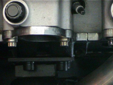 1979 Ford Bronco - Detail of an engine part, showing bolts and a handwritten number 2.