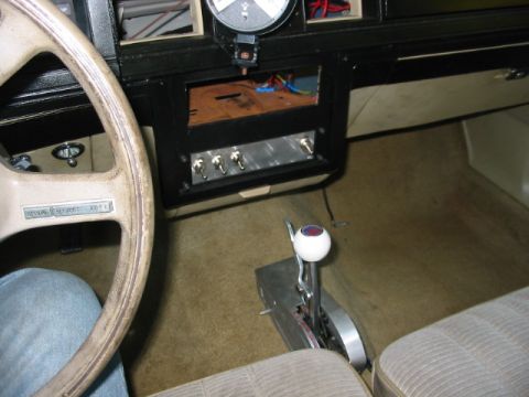 1985 Ford LTD Crown Victoria - The interior of a car features a steering wheel, a dashboard with custom switches, and a floor-mounted shifter.