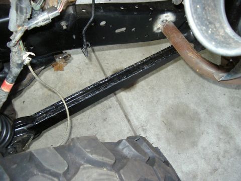 1985 Ford Bronco - Close-up view of vehicle suspension parts and a tire tread, with visible wiring and exhaust components.