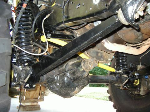 1985 Ford Bronco - Undercarriage view of a vehicle's front axle and suspension system, showing springs and shocks.