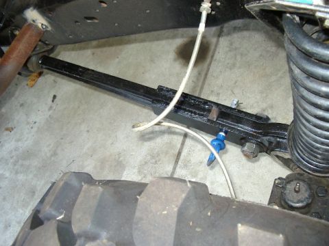 1985 Ford Bronco - Close-up view of a vehicle's front suspension components, including a metal arm and coil spring.