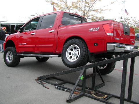 1977 Ford F-150 - A red pickup truck is positioned on a metal ramp, displaying its side profile and 4x4 badging.