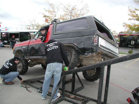 1977 Ford F-150 - A two-tone Ford Bronco is positioned on a ramp as individuals work on its undercarriage.