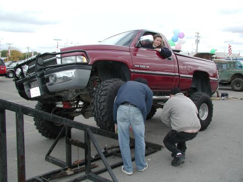 1977 Ford F-150 - A lifted red Dodge Ram 1500 pickup truck is shown with two men inspecting its undercarriage.