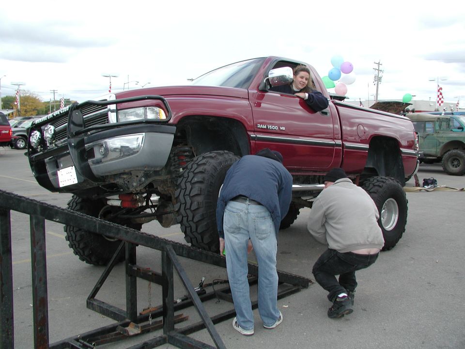 Red lifted Dodge Ram 1500 pickup truck with men working underneath