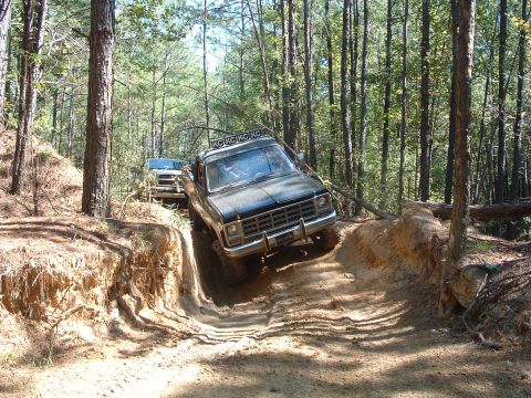 1993 Ford Bronco - Off-roading adventure with multiple trucks on a challenging forest trail.
