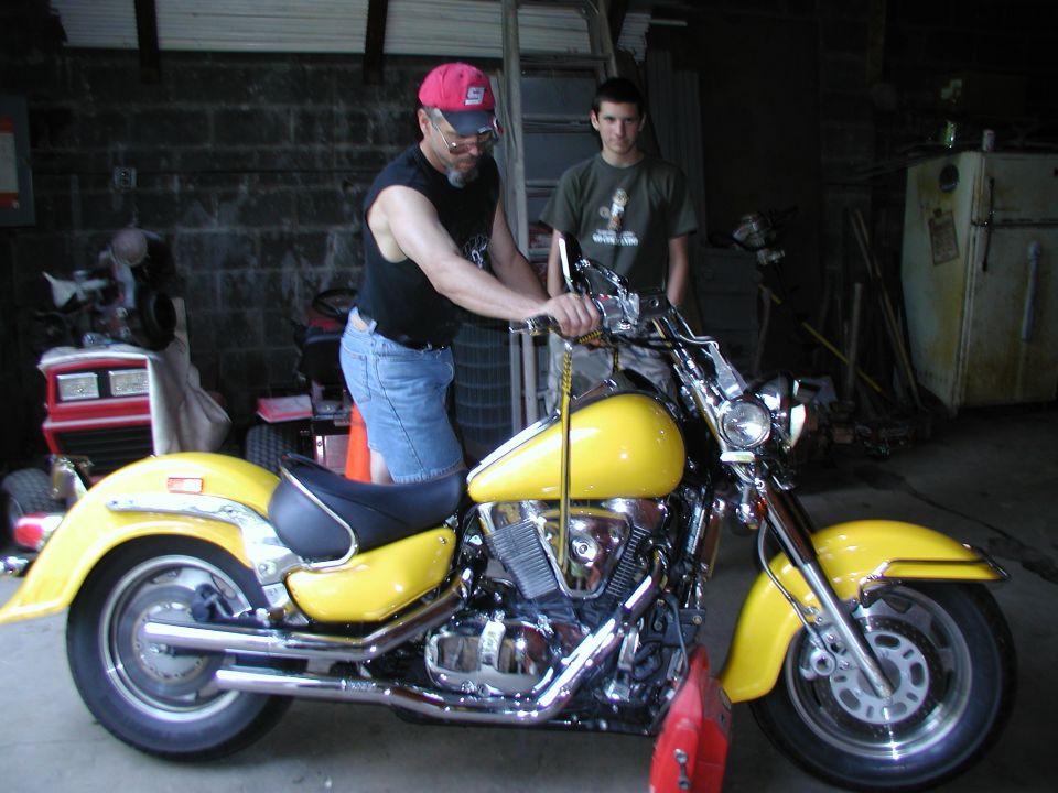 Yellow Honda VTX cruiser motorcycle in a garage with two men