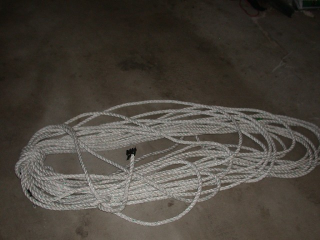 Coiled white rope on a concrete floor. A black connector is visible on the rope