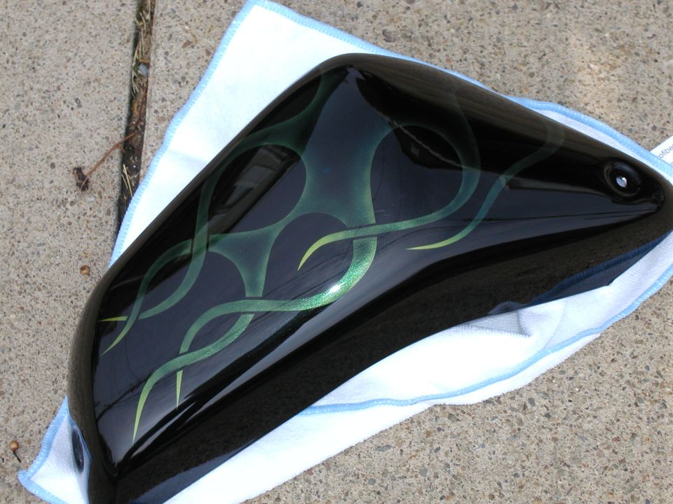 Black motorcycle fuel tank with green ghost flames on a towel