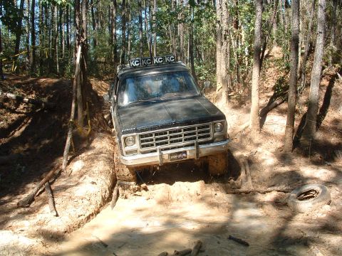 1993 Ford Bronco - This SUV is tackling a challenging muddy trail, its KC lights illuminating the path ahead.
