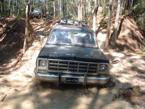 1993 Ford Bronco - Off-road truck navigating a muddy trail with another vehicle in the background.