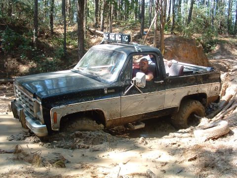 1993 Ford Bronco - A driver navigates a muddy off-road trail, getting stuck in the mire.