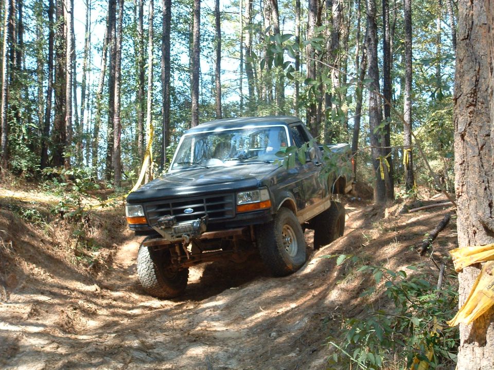 1993 Ford Bronco navigating a dirt path in a wooded area
