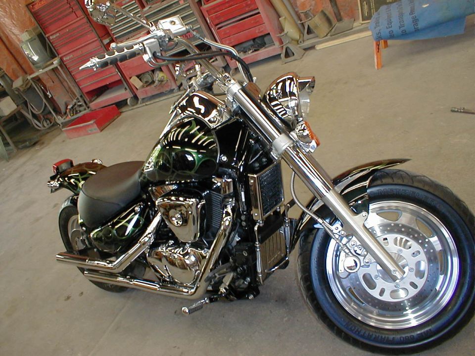 Black cruiser motorcycle with green flame paint, polished disc wheels, chrome pipes