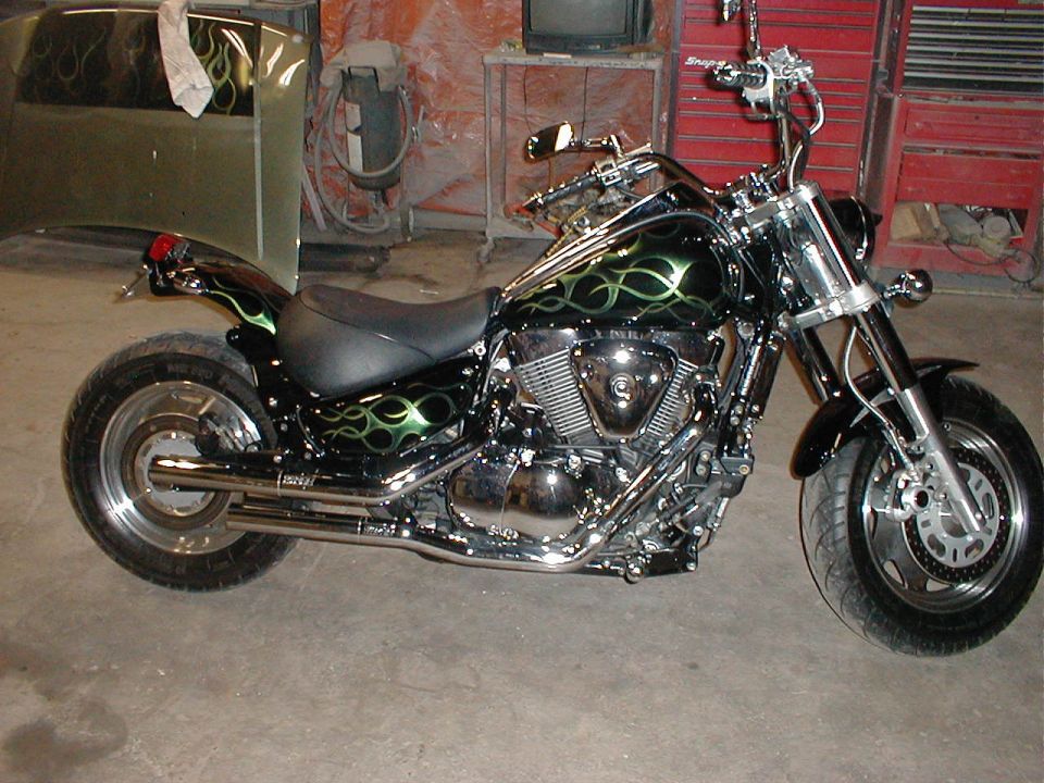 Black cruiser motorcycle with green flames and chrome engine in a garage