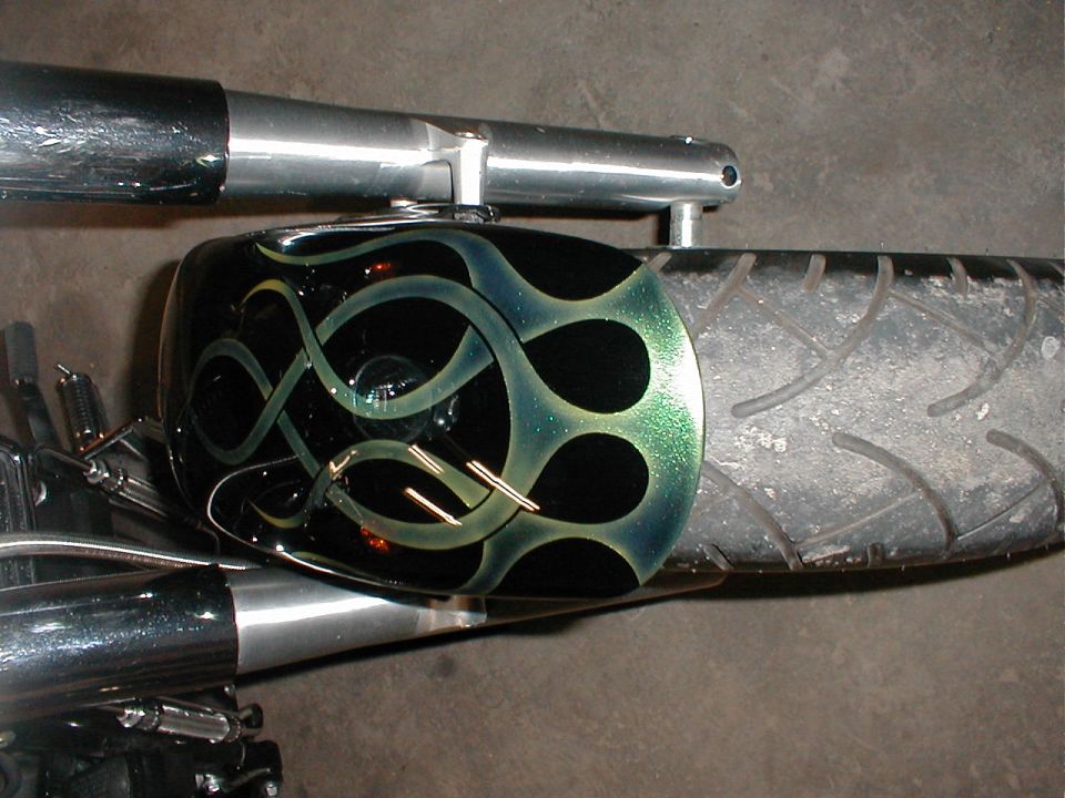 Motorcycle fender with black and green flame paint job and chrome exhaust pipe