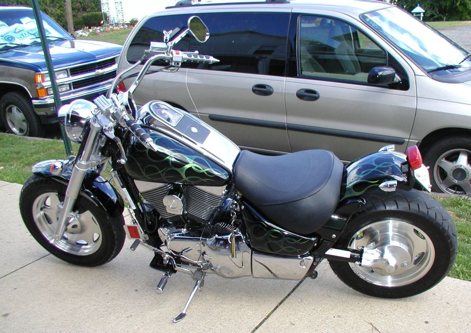 Black Suzuki V-twin cruiser with green flame paint parked on a driveway, left side