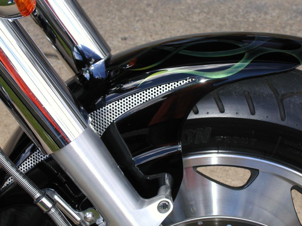 Black motorcycle front fender with green flames over chrome wheel and fork