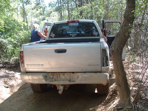1993 Ford Bronco - A Dodge Ram pickup truck is parked on a dirt trail surrounded by trees, with people getting in and out.