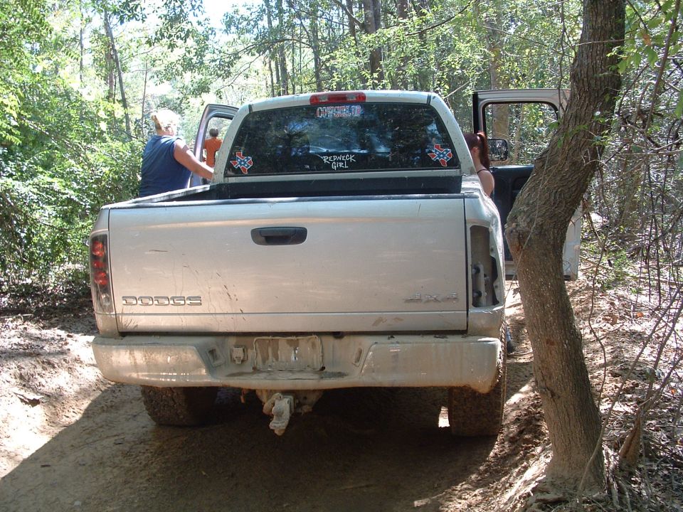 Silver Dodge Ram pickup truck with doors open, parked on a dirt trail in woods