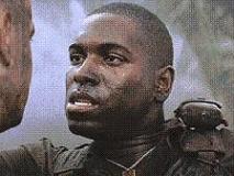 1991 Ford Bronco - A soldier's face is shown in close-up, sweat and dirt streaked across his skin as he looks intently at someone off-camera.