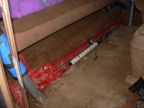 1991 Ford Bronco - A red hi-lift jack and other items are stored on the floor of a vehicle's interior.
