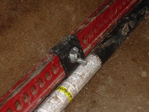 1991 Ford Bronco - Close-up of a red hi-lift jack part and a black pipe with text, suggesting off-road or utility equipment.