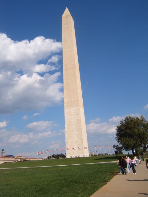1988 Ford Bronco - The Washington Monument stands tall under a partly cloudy sky, with flags and visitors visible at its base.