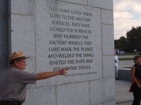 1988 Ford Bronco - A park ranger gestures towards an inscription on a large stone monument, with other visitors in the background.