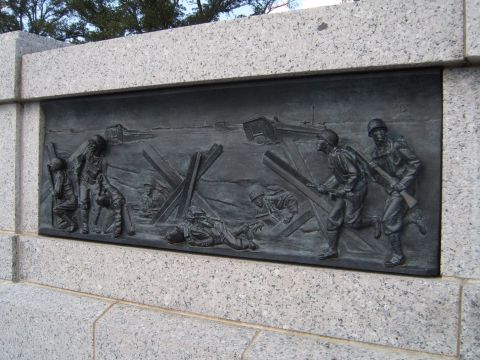 1988 Ford Bronco - A detailed relief sculpture captures a historical scene of soldiers navigating a beach landing, complete with obstacles and military action.