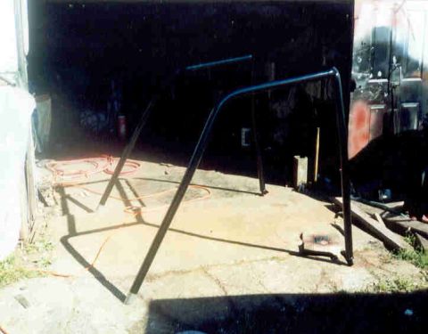 1989 Ford Bronco - A black roll bar is seen in a garage setting, possibly undergoing installation or modification.