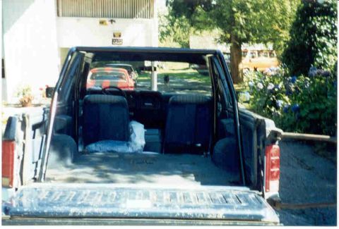 1989 Ford Bronco - View into the rear of a pickup truck, showing the interior and a glimpse of other vehicles outside.