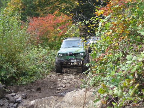 1990 Ford Bronco - A 1990 Ford Bronco navigates a challenging rocky trail during autumn.