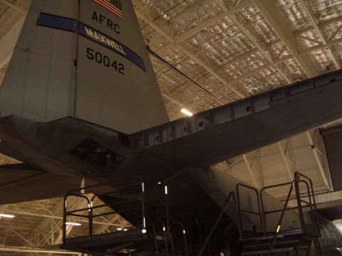 1988 Ford Bronco - The tail of a large military cargo aircraft is visible inside a hangar, showing its identification numbers and markings.