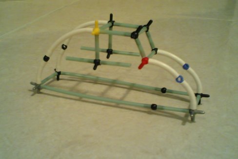 Small plastic-rod scale model of a tube-frame buggy roll cage on carpet